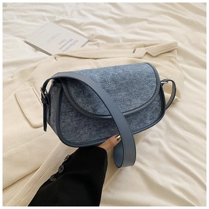 Detail of blue denim hobo bag with quilted diamond pattern on beige striped blazer