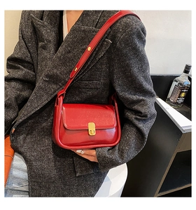 Detail of vintage red shiny leather crossbody bag with golden hardware buckle on a suit