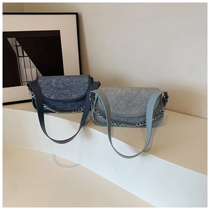 Detail view of denim texture crossbody bags in navy and light blue with silver chains