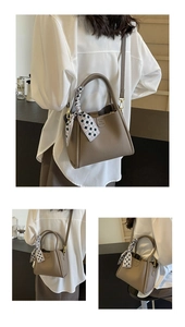 Dettaglio borsa in pelle martellata marrone con foulard geometrico e fibbie dorate