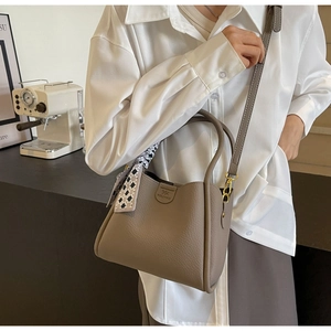 Dettaglio della borsa a secchiello in pelle kaki con grana litchi e foulard decorativo