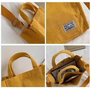 Detail view of yellow corduroy tote showing adjustable strap, brand tag and interior space