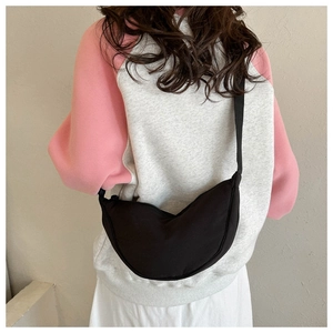 Detail of minimalist black canvas crescent bag showing adjustable strap and draping effect