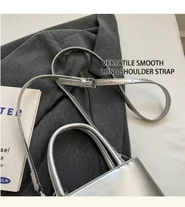 Detail showing smooth adjustable shoulder strap on silver glossy crossbody bucket bag