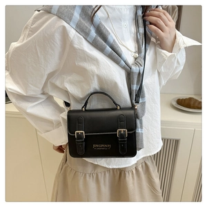 Dettaglio di una piccola borsa a tracolla nera vintage con fibbie decorative su modella