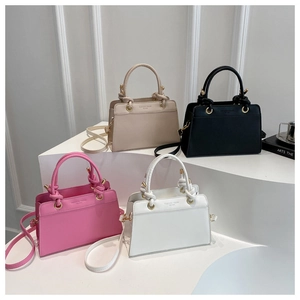 Display of faux leather handbags in beige black pink and white on a tiered stand