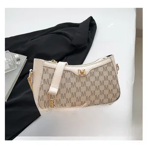 Detail of French style underarm bag showing beige leather texture and golden M logo