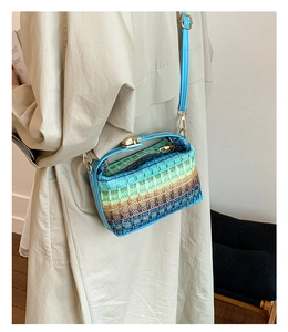 Dettaglio borsa in paglia intrecciata sfumata con finiture in pelle blu e chiusura d'oro