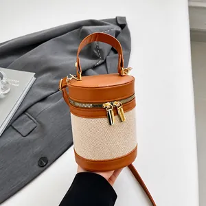 Detailed shot of cylinder bucket bag with brown lychee leather and woven fabric texture
