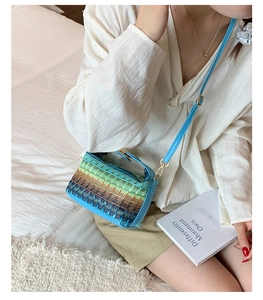 Macro detail of rainbow woven straw bag showing gradient texture and gold chain strap