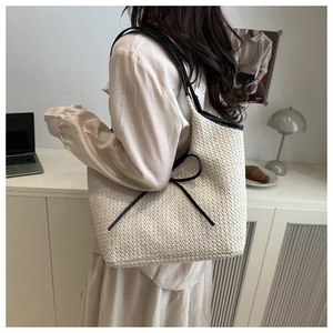 Détail d'un sac cabas tissé beige orné d'un nœud noir et d'une bandoulière fine