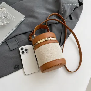 Detail of a cylindrical bucket bag featuring brown leather and beige canvas textures