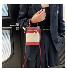 Detail of burgundy leather and beige canvas cylinder bucket bag with dual zippers