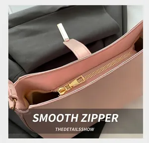Close-up of smooth light gold zipper and pink leather detail on retro shoulder bag