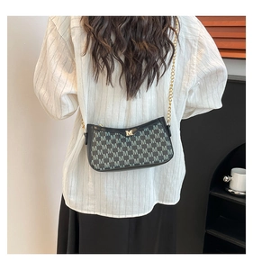 Detail of vintage black baguette bag with grey M pattern and gold metal chain strap