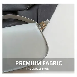 Close-up of premium stitching and gold hardware on light gray leather shoulder bag