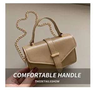 Detail of minimalist beige handbag featuring polished leather and golden chain strap