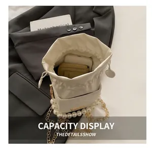 Detail shot of white pearl bucket bag showing spacious interior for phone and wallet
