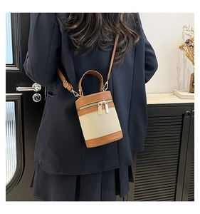 Detail of color-block canvas bucket bag featuring brown leather trim and gold zippers