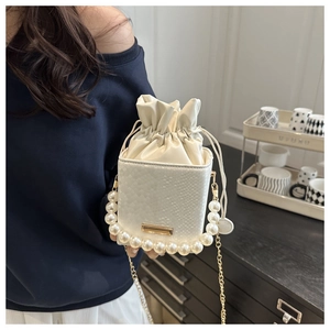 Detail of white snake-embossed bucket bag with large pearl handle and gold chain strap