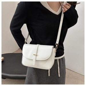Detail of white leather crossbody bag with sleek gold bar closure and thin strap