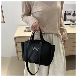 Detail of black tote bag with silver bow accent and versatile shoulder strap for daily use