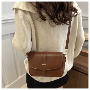 Klassische braune Umhängetasche aus mattem Leder mit Goldschnalle an einem Model