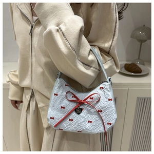 Detail of light blue handbag with red bows and Meow Miow heart charm on fabric texture