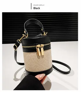 Détail d'un sac cylindrique en cuir noir et toile beige avec des fermetures dorées