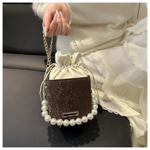 Detail of snake skin texture bucket bag with pearl handle and golden chain strap
