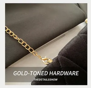 Close-up of golden lobster clasp and chain hardware on high-quality black velvet bag