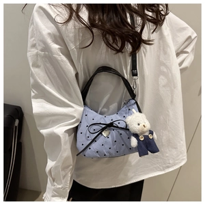 Détail d'un sac à main rayé bleu avec motif de cœurs et charmant pendentif d'ours blanc