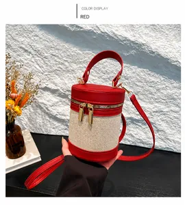 Détail du sac seau cylindrique en cuir rouge et toile beige avec zip et bandoulière