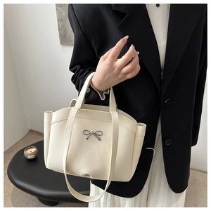 Detailed view of an off-white PU leather tote bag with a silver bow metal buckle