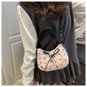 Detail of pink bubble texture shoulder bag with black bows and silver heart charm