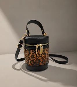 Détail d'un sac seau cylindrique en tissu léopard et cuir noir avec finitions dorées