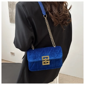 Blue velvet shoulder bag with gold chain strap and diamond quilting shown on a model