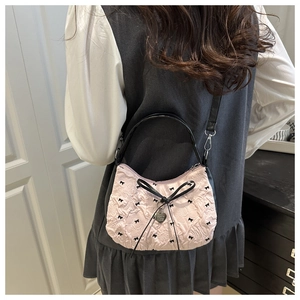 Detail of pink crescent bag showing black bow patterns and heart metal pendant charm