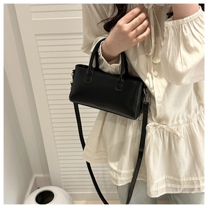 Minimalistische zwarte lederen mini-handtas op een witte ruches-shirt voor een chique look