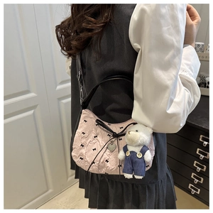 Vue détaillée du sac croissant rose plissé avec broderie nœud noir et breloque ours