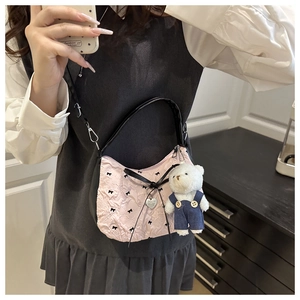 Detail of pink ruffled handbag with black bows, silver heart tag, and plush bear charm