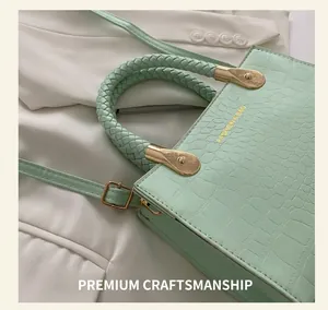 Detail of mint green crocodile pattern bag with braided handle and gold metal hardware