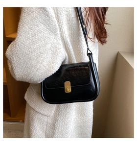 Close-up of black glossy shoulder bag featuring a vintage gold striped metal buckle