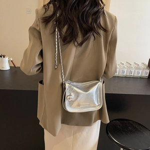 Sac bandoulière argenté avec chaîne et texture en cuir plissé porté par un mannequin