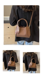 Dettaglio di una borsa a secchiello in pelle marrone con foulard di seta sul manico