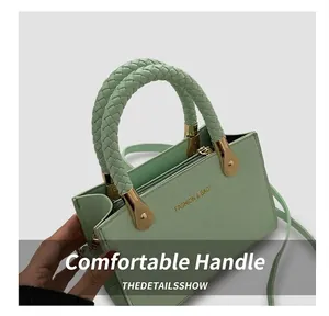 Detail of mint green crocodile-textured leather handbag with woven handles and gold hardware