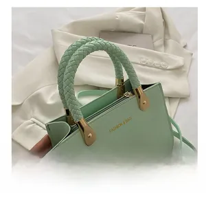 Detail of mint green crocodile-textured leather handbag with woven handles and gold hardware