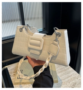 Detail of white crocodile embossed mini handbag with large square buckle and braided handle