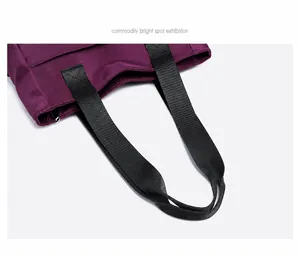 Detail van paarse nylon draagtas met versterkte X-stiksels op zwarte geweven handgrepen