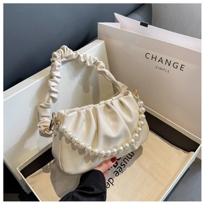 Detail of cream pleated cloud bag with large pearl strap in elegant gift box packaging